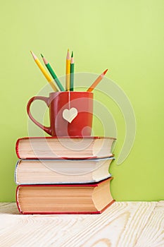 Stack of hardback books, diary on wooden deck table and green background. Back to school. Copy Space. Education