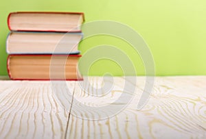 Stack of hardback books, diary on wooden deck table and green background. Back to school. Copy Space. Education