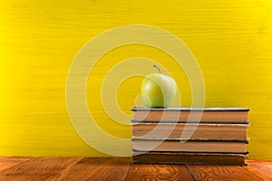 Stack of hardback books, diary on wooden deck table and yellow background. Back to school. Copy Space. Education
