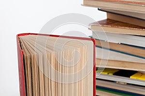 Stack of hardback books and old open book on white wall background. Search for relevant and necessary information.