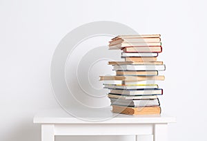 Stack of hardback books on the white table. Search for relevant and necessary information.