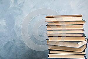 Stack of hardcover books on blue background. Space for text