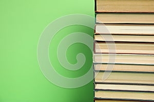 Stack of hardcover books on green background. Space for text