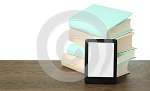 Stack of hardcover books and modern e-book on wooden table against white background. Space for text