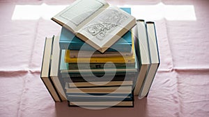 Books with worn spines arranged on a table adorned with a pair