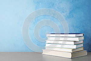 Stack of hardcover books on table against color background