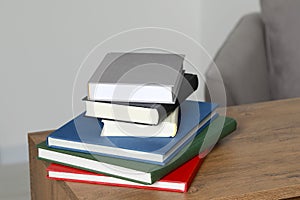 Stack of hardcover books on wooden table indoors