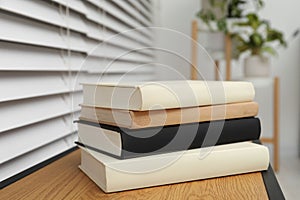 Stack of hardcover books on wooden table indoors