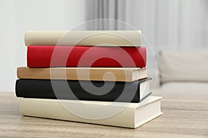 Stack of hardcover books on wooden table indoors