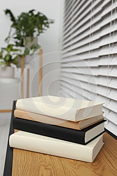 Stack of hardcover books on wooden table indoors