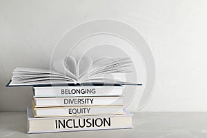 Stack of hardcover books with words Belonging, Diversity, Equity, Inclusion on table against white background