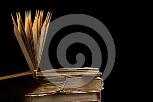 Stack of hardcover old books with an open book on a dark background. Bookshelf shop, Knowledge publications, literature. Bookish