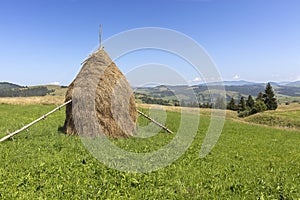 Stack of hay on a mountain meadow on a hillside.