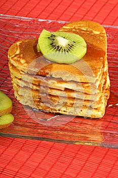 Stack of heart-shaped pancakes with syrup and kiwi fruit