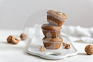 Stack of Homemade banana muffins with walnut on white background
