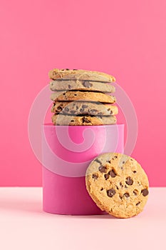 A stack of homemade cookies with chocolate chips on a pink stand on a pink background. Bakery.