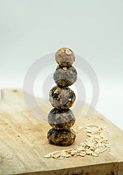 Stack of homemade energy balls on wooden chopping board isolated