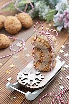 Stack of homemade oatmeal cookies on sleigh. Christmas healthy cookies, biscuits. Rustic wooden table. Winter decoration