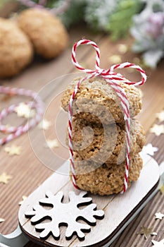 Stack of homemade oatmeal cookies on sleigh. Christmas healthy cookies, biscuits. Rustic wooden table. Winter decoration