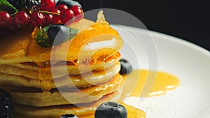 Stack of homemade pancakes or crepes decorated on top with forest berries - red currant, blackberry and blueberry
