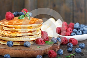 Stack of homemade pancakes with fresh blueberries, raspberries and maple syrup.