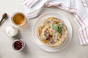 Stack of homemade pancakes served with honey and berries,