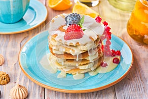 Stack of homemade pancakes with strawberrie, banana and red currant on a blue plate