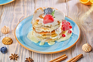 Stack of homemade pancakes with strawberrie, banana and red currant on a blue plate