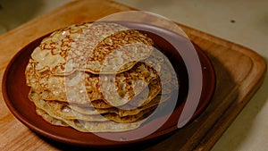 A stack of hot pancakes. Man put pancake on top. Pancakes with holes. Pancake week. Ukrainian, Russian tradition.