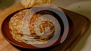 A stack of hot pancakes. Man put pancake on top. Pancakes with holes. Pancake week. Ukrainian, Russian tradition.