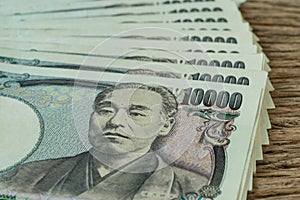 Stack of japanese yen banknotes on wooden table as financial safe haven concept