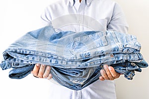 Stack of jeans in hand of seller on the light background