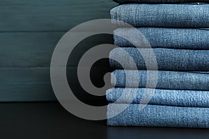 Stack of jeans pants on black table