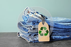 Stack of jeans with recycling label on grey table