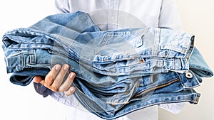 Stack of jeans in seller& x27;s hands on the light background