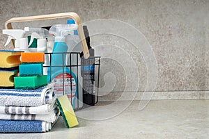 Stack of kitchen towels, multi-colored sponges and a basket of detergents on the kitchen table