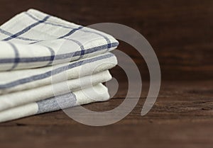 A stack of kitchen towels are stacked on an old rustic table