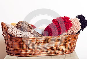 Stack of knitted hats and yarns in a basket