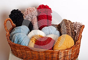 Stack of knitted hats and yarns in a basket