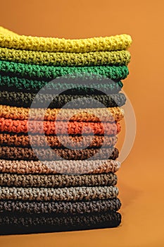 Stack of knitted material from multicolored threads on a orange background. Copy, empty space for text