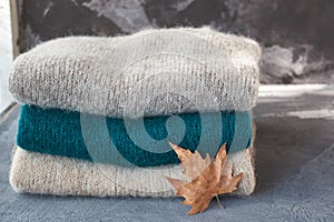 Stack of knitted sweaters with a leaf isolated on the grey background