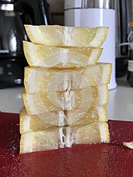 A stack of lemon wedges on a red cutting board - LEMONS - FRUIT