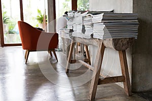 Stack of magazine books on wooden table shelf in living room