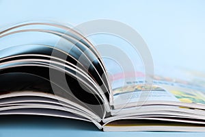 Stack of magazines on light blue background, closeup