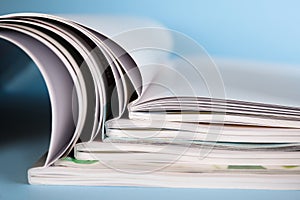 Stack of magazines on light blue background, closeup