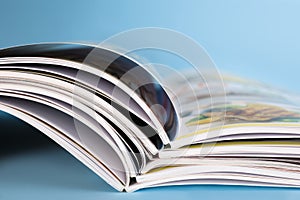 Stack of magazines on light blue background, closeup