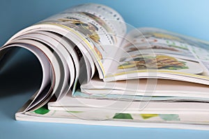 Stack of magazines on light blue background, closeup