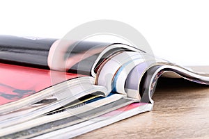 Stack of magazines on wooden table isolated on white background