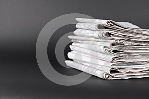 Stack of many newspapers on grey background, space for text
