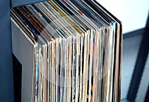 Stack of many vinyl records in old color covers on a shelf side view